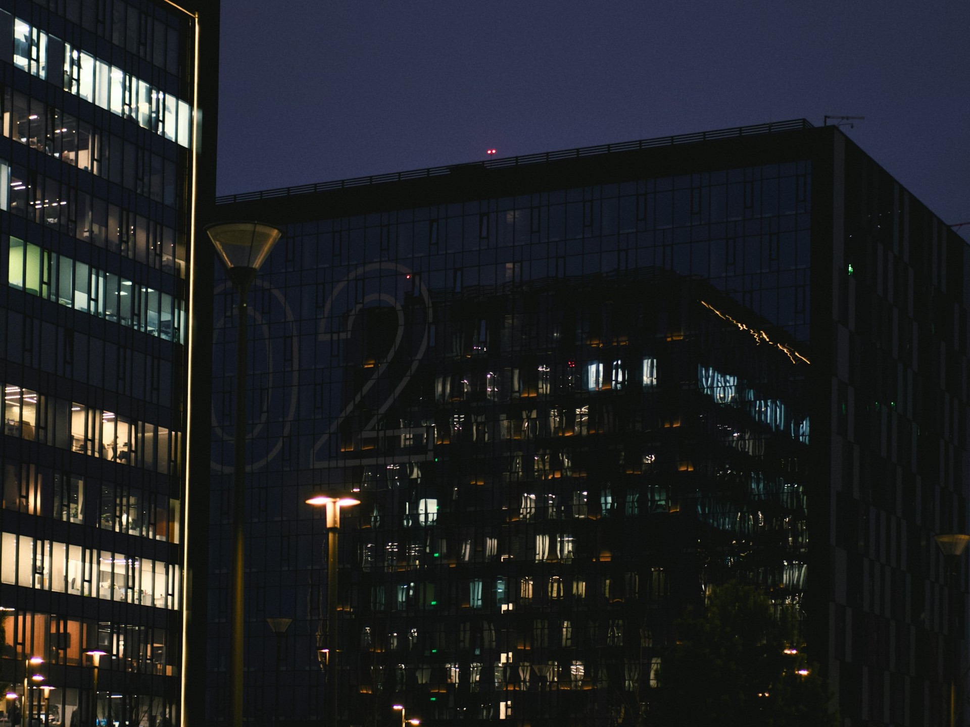 Class-A office tower at night with lit curtain-wall windows